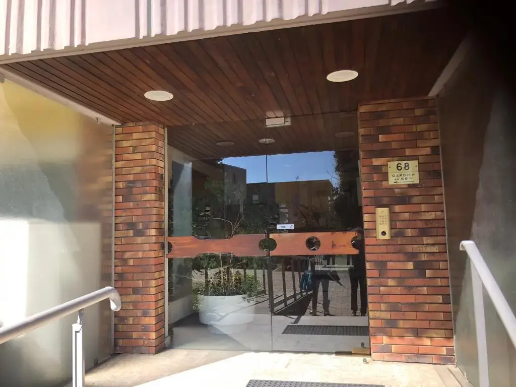 Porte d'entrée vitrée de l'immeuble avec le numéro 68 et l'interphone