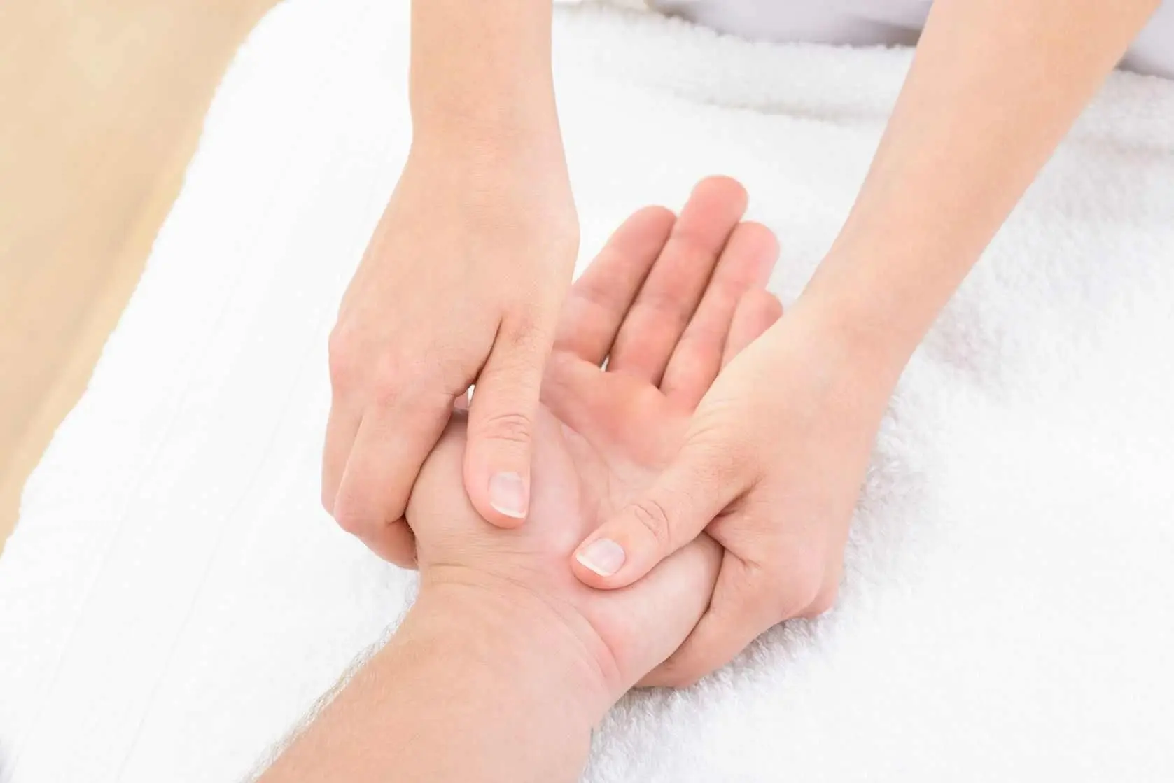 Pression exercée sur une zone réflexe de la main pendant une séance de réflexologie